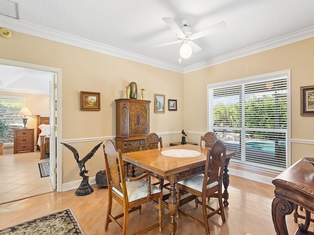 tiled dining space with ceiling fan and crown molding