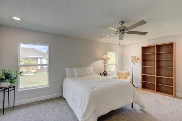 carpeted bedroom with ceiling fan, baseboards, and multiple windows