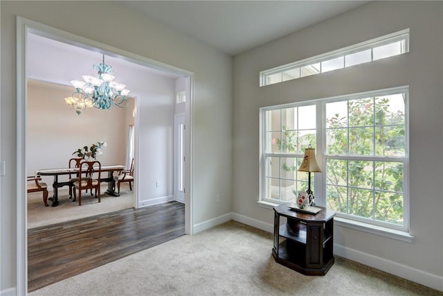 carpeted foyer entrance with baseboards and a notable chandelier