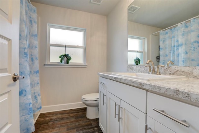 bathroom featuring wood finished floors, visible vents, toilet, and plenty of natural light