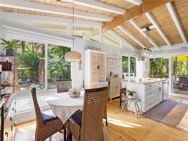 sunroom featuring lofted ceiling with beams, an inviting chandelier, and sink