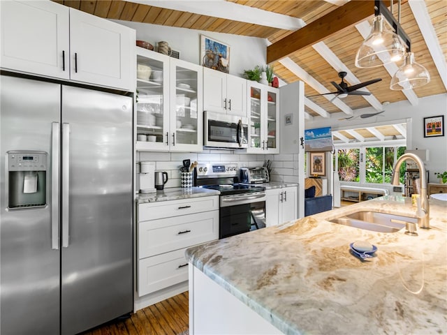 kitchen with white cabinets, vaulted ceiling with beams, appliances with stainless steel finishes, and tasteful backsplash