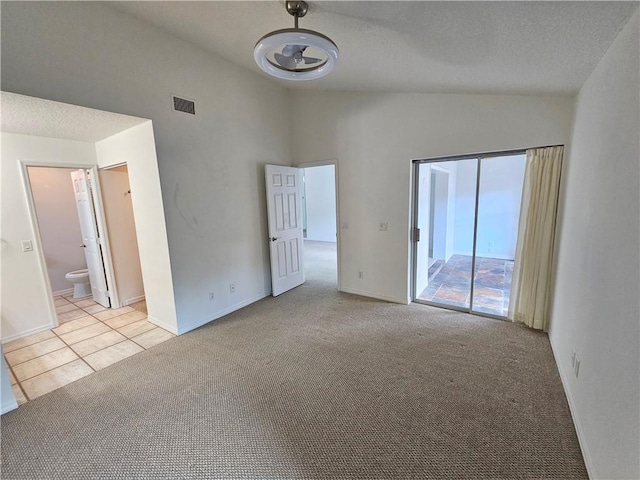 542 9th Pl, Vero Beach, FL 32960 - empty room with vaulted ceiling, light colored carpet, light tile patterned flooring, and a textured ceiling