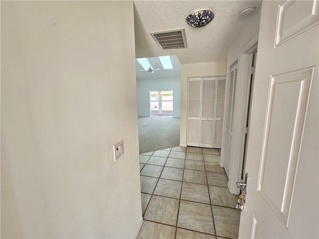542 9th Pl, Vero Beach, FL 32960 - hallway with a skylight, light tile patterned floors, light carpet, and a textured ceiling
