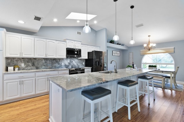 kitchen with white cabinetry, hanging light fixtures, sink, and stainless steel appliances