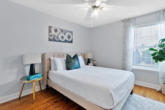 bedroom with multiple windows, wood-type flooring, ceiling fan, and a textured ceiling