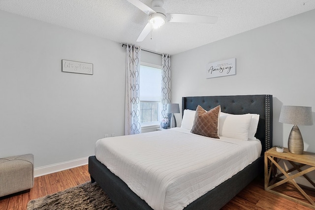 bedroom with ceiling fan, wood-type flooring, and a textured ceiling