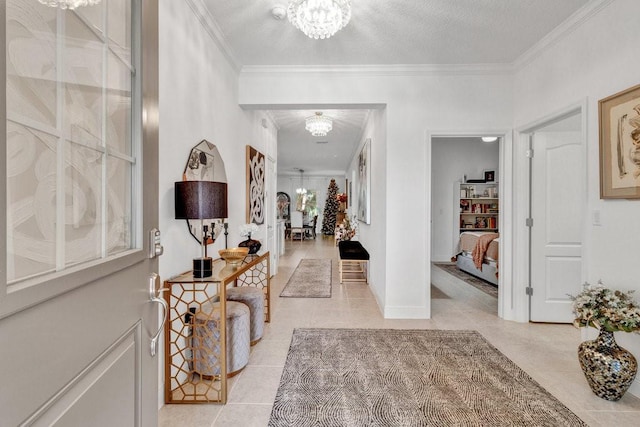 entrance foyer with a chandelier, a textured ceiling, crown molding, and light tile patterned flooring