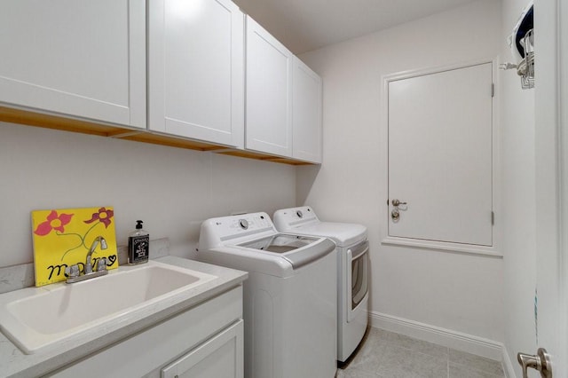 laundry area featuring a sink, cabinet space, light tile patterned floors, baseboards, and washing machine and clothes dryer