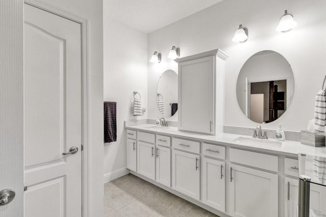 full bathroom with a sink, baseboards, double vanity, and tile patterned flooring