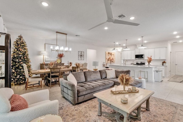 living area featuring visible vents, recessed lighting, ceiling fan with notable chandelier, light tile patterned flooring, and a textured ceiling