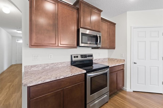 kitchen featuring light hardwood / wood-style flooring, stainless steel appliances, and a textured ceiling