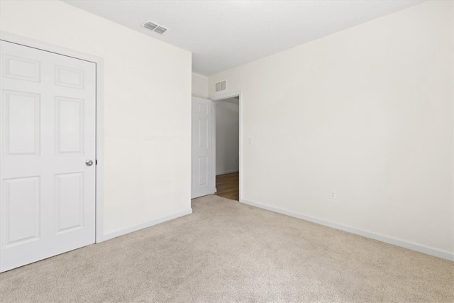 unfurnished bedroom with a closet and light colored carpet