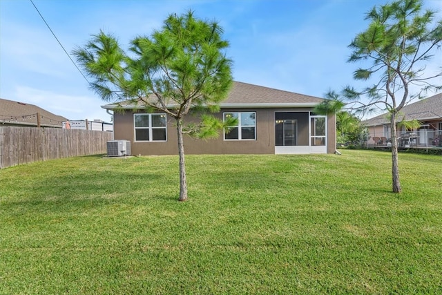 rear view of property featuring central air condition unit, a sunroom, and a yard