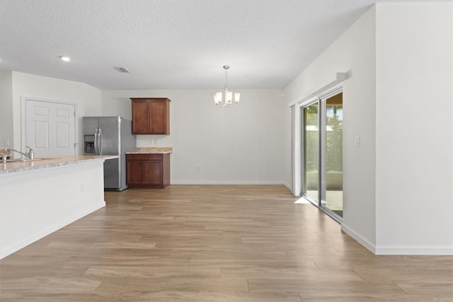 kitchen featuring stainless steel fridge, light hardwood / wood-style flooring, hanging light fixtures, and a notable chandelier