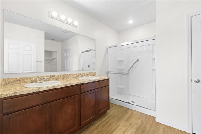 bathroom featuring hardwood / wood-style floors, vanity, and a shower with door