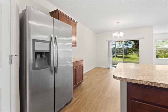 kitchen with light wood-type flooring, stainless steel fridge, pendant lighting, and a healthy amount of sunlight