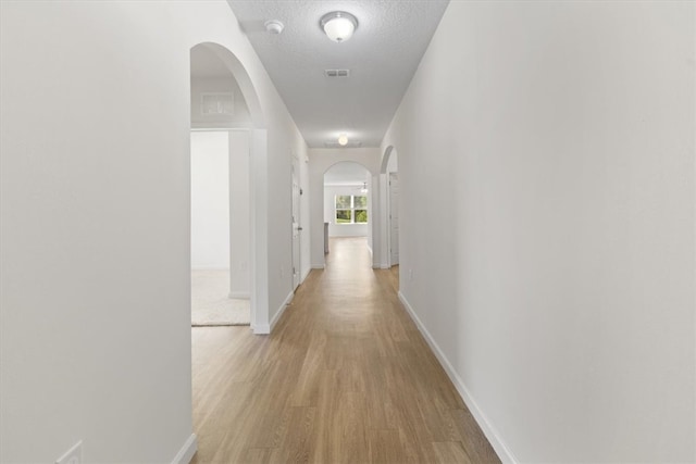 hallway featuring a textured ceiling and light hardwood / wood-style flooring