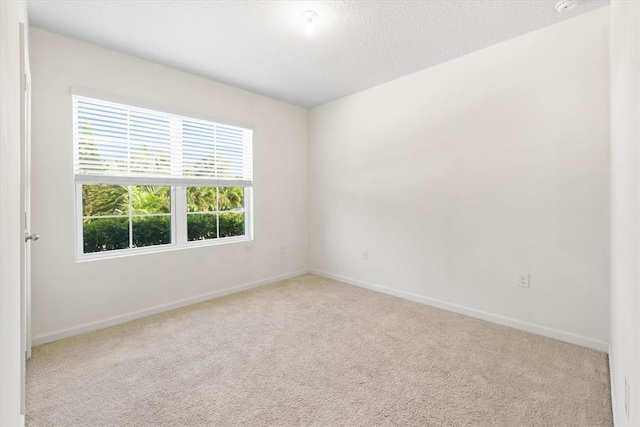 empty room with light carpet and a textured ceiling