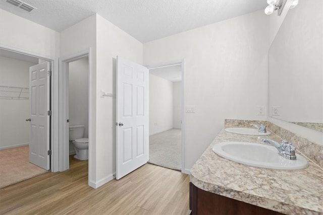 bathroom with vanity, toilet, wood-type flooring, and a textured ceiling