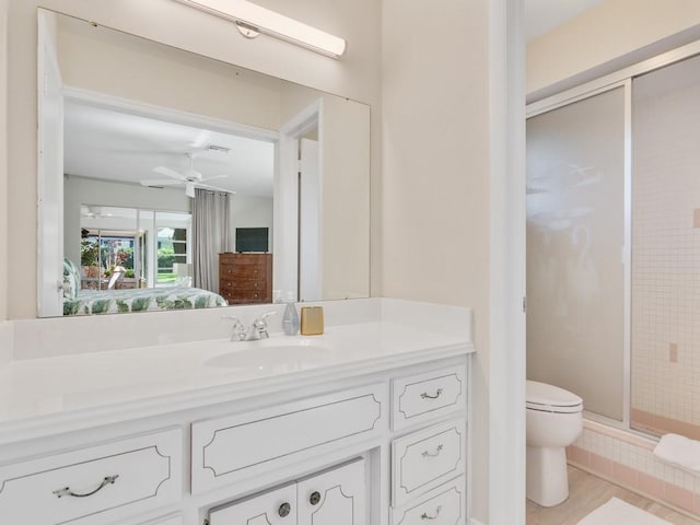 bathroom featuring ceiling fan, toilet, a shower with door, and vanity