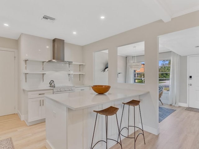 kitchen with white cabinets, a kitchen breakfast bar, electric stove, light hardwood / wood-style flooring, and wall chimney exhaust hood