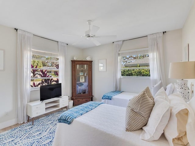 bedroom with multiple windows, hardwood / wood-style flooring, and ceiling fan