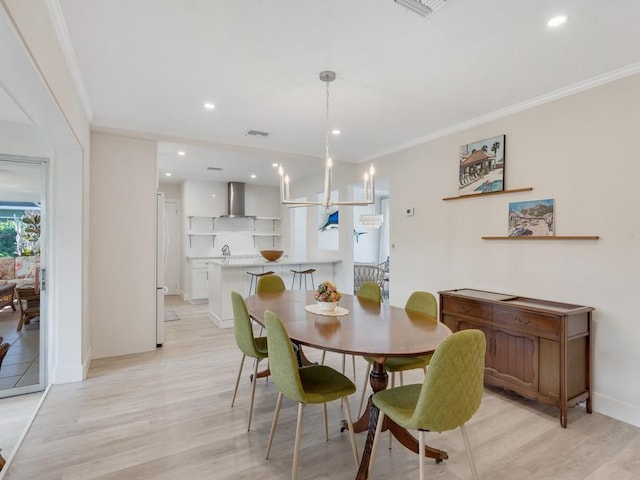 dining room with a chandelier, light hardwood / wood-style flooring, and ornamental molding