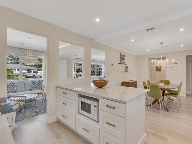 kitchen with white cabinetry, light hardwood / wood-style flooring, and hanging light fixtures