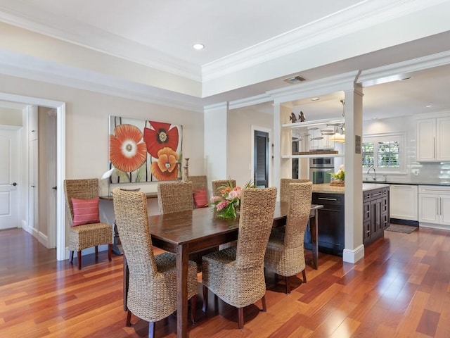 dining space with ornamental molding, wood finished floors, visible vents, and recessed lighting