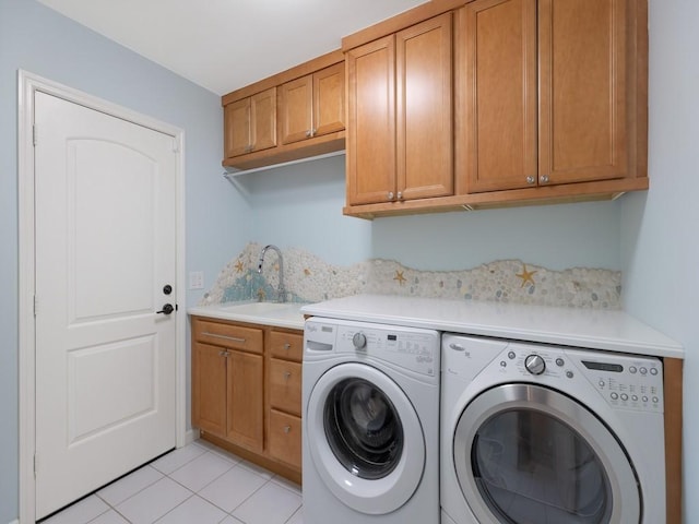 washroom with cabinet space, a sink, washing machine and clothes dryer, and light tile patterned floors