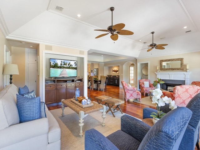 living room featuring visible vents, crown molding, a fireplace, and wood finished floors