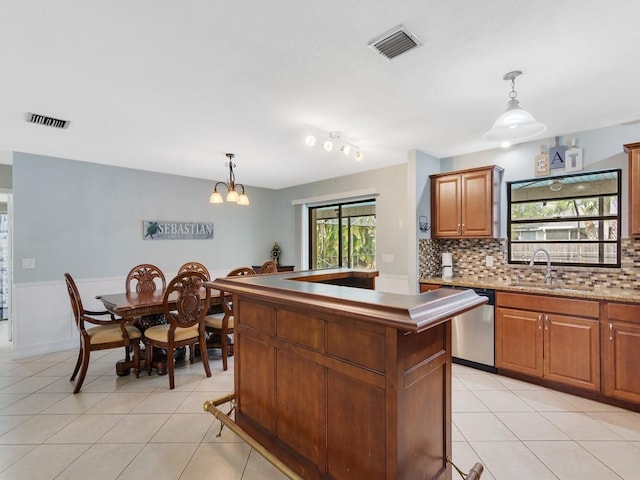 kitchen with a kitchen island, pendant lighting, dishwasher, sink, and light tile patterned floors