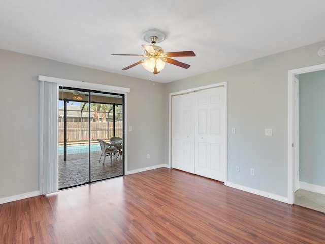 unfurnished bedroom featuring dark hardwood / wood-style flooring, access to exterior, a closet, and ceiling fan