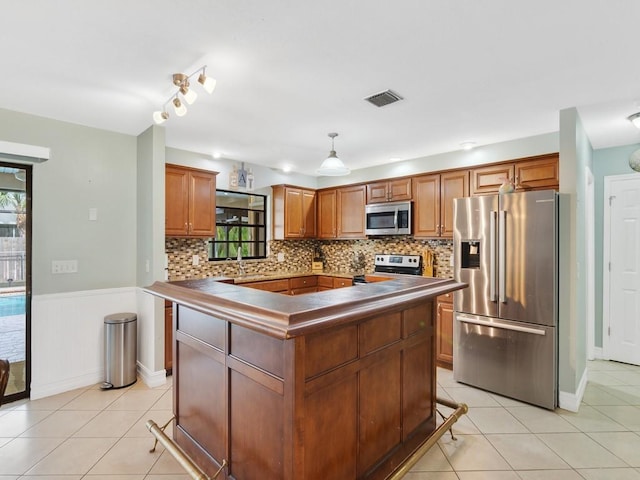 kitchen featuring a healthy amount of sunlight, stainless steel appliances, a center island, and hanging light fixtures