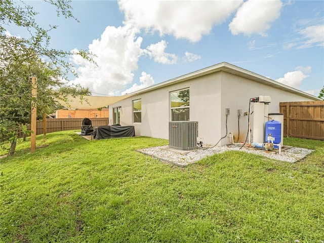 rear view of house with cooling unit and a yard