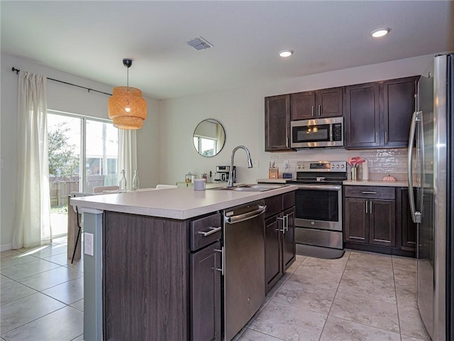 kitchen with decorative light fixtures, tasteful backsplash, sink, dark brown cabinetry, and stainless steel appliances