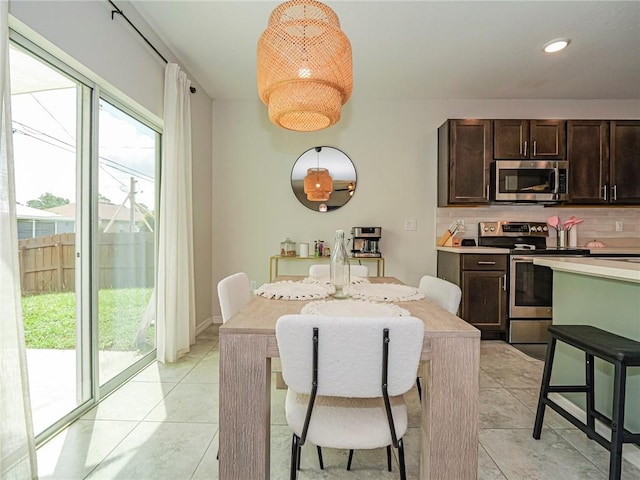 kitchen with a breakfast bar, stainless steel appliances, tasteful backsplash, dark brown cabinetry, and light tile patterned flooring