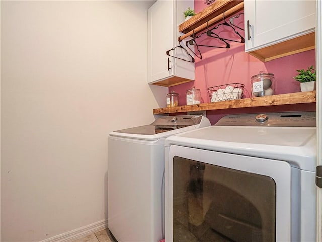 clothes washing area featuring light tile patterned floors, washer and clothes dryer, and cabinets