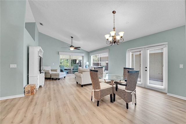 dining space featuring ceiling fan with notable chandelier, light hardwood / wood-style flooring, a textured ceiling, and lofted ceiling