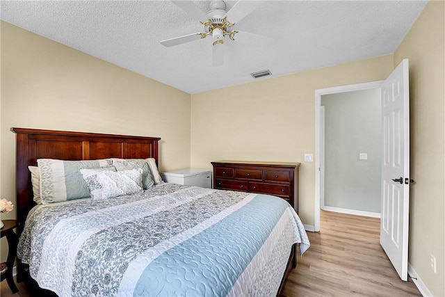 bedroom with ceiling fan, a textured ceiling, and light wood-type flooring