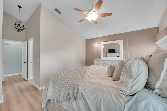 bedroom featuring light hardwood / wood-style floors, ceiling fan with notable chandelier, and high vaulted ceiling