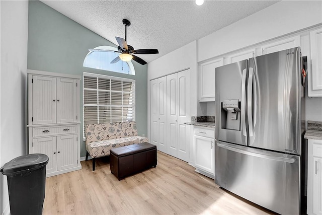 interior space with light wood-type flooring, ceiling fan, a textured ceiling, and lofted ceiling