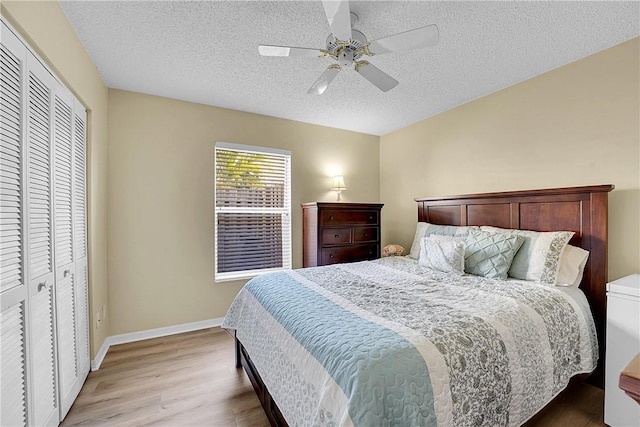 bedroom featuring a closet, ceiling fan, light hardwood / wood-style floors, and a textured ceiling