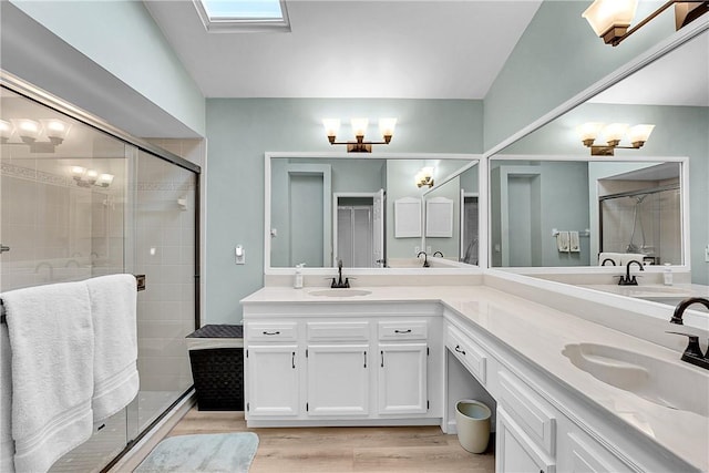 bathroom featuring vanity, a skylight, a shower with door, and hardwood / wood-style flooring