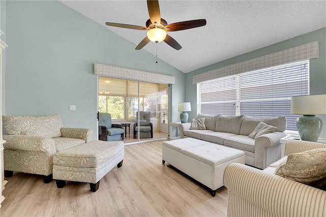 living room featuring ceiling fan, light hardwood / wood-style flooring, a textured ceiling, and lofted ceiling