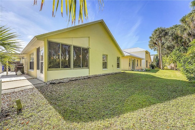 rear view of property with a patio and a lawn