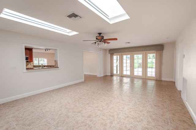 empty room with a skylight, ceiling fan, french doors, and light tile patterned floors