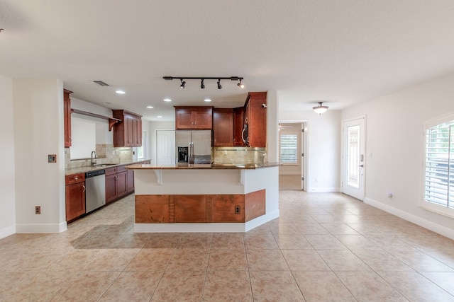 kitchen with a breakfast bar, backsplash, sink, light tile patterned floors, and stainless steel appliances