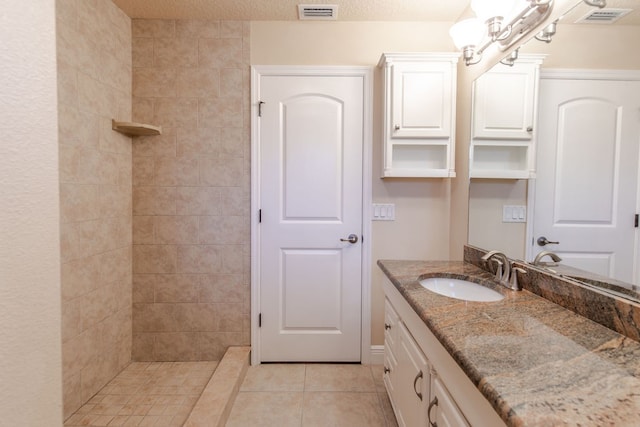 bathroom featuring a tile shower, tile patterned flooring, and vanity